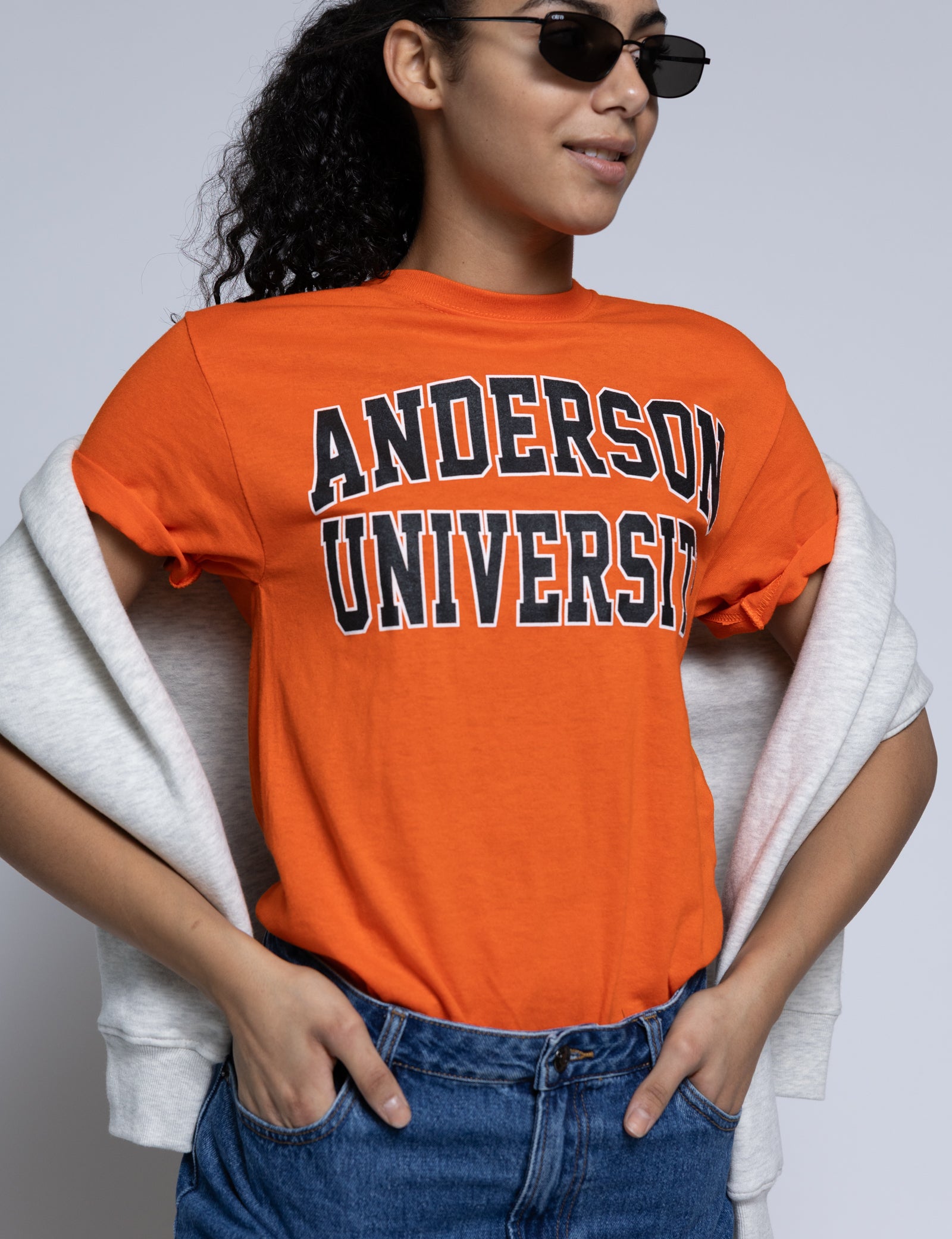 Person wearing an orange 'Anderson University' t-shirt with sunglasses and a crew draped over their shoulders.