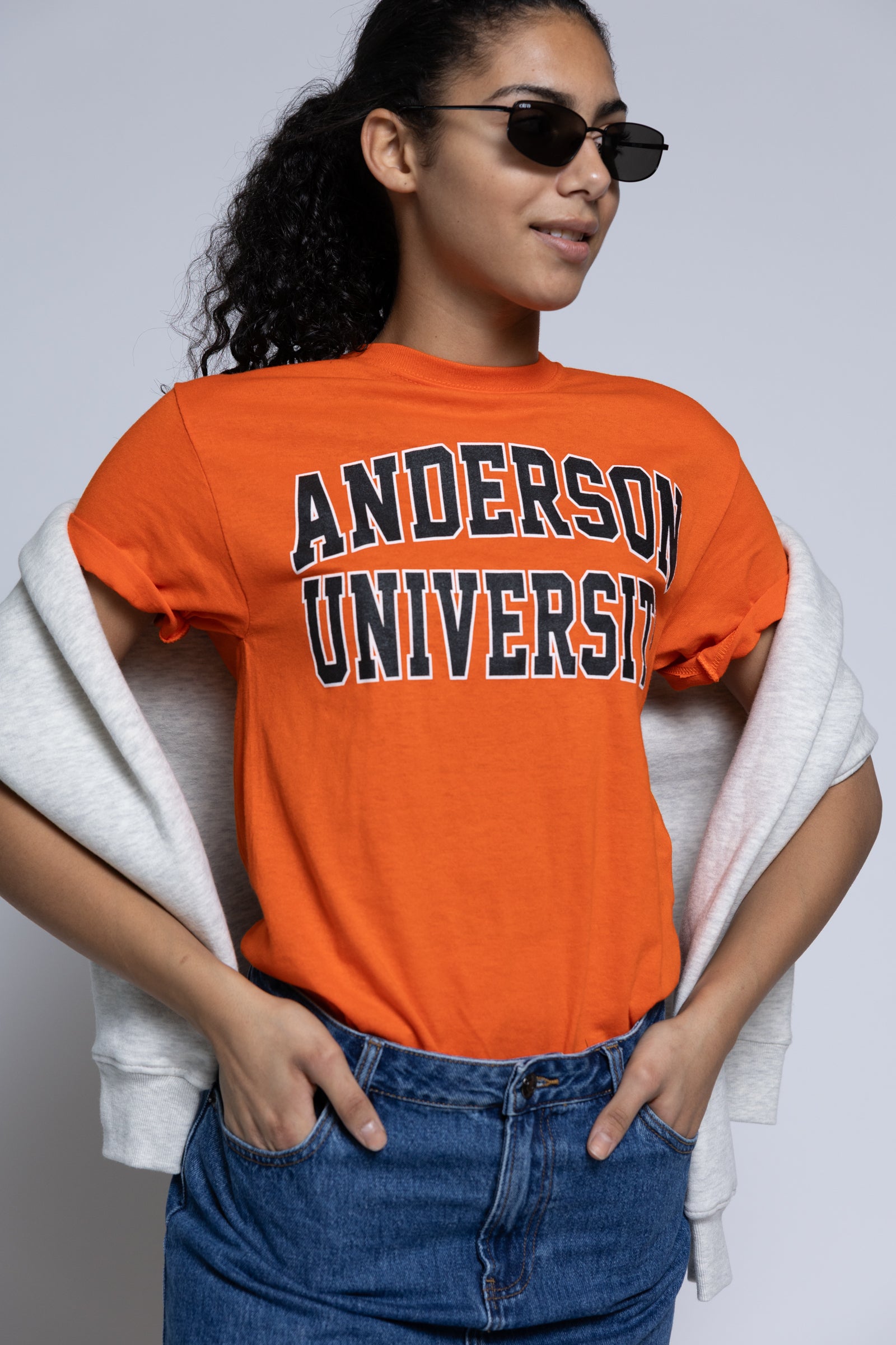 Person wearing an orange 'Anderson University' t-shirt with sunglasses and a crew draped over their shoulders.