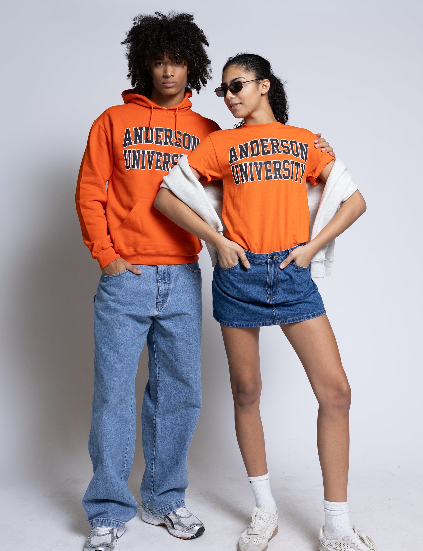 Two people wearing orange Anderson University clothing on a plain background