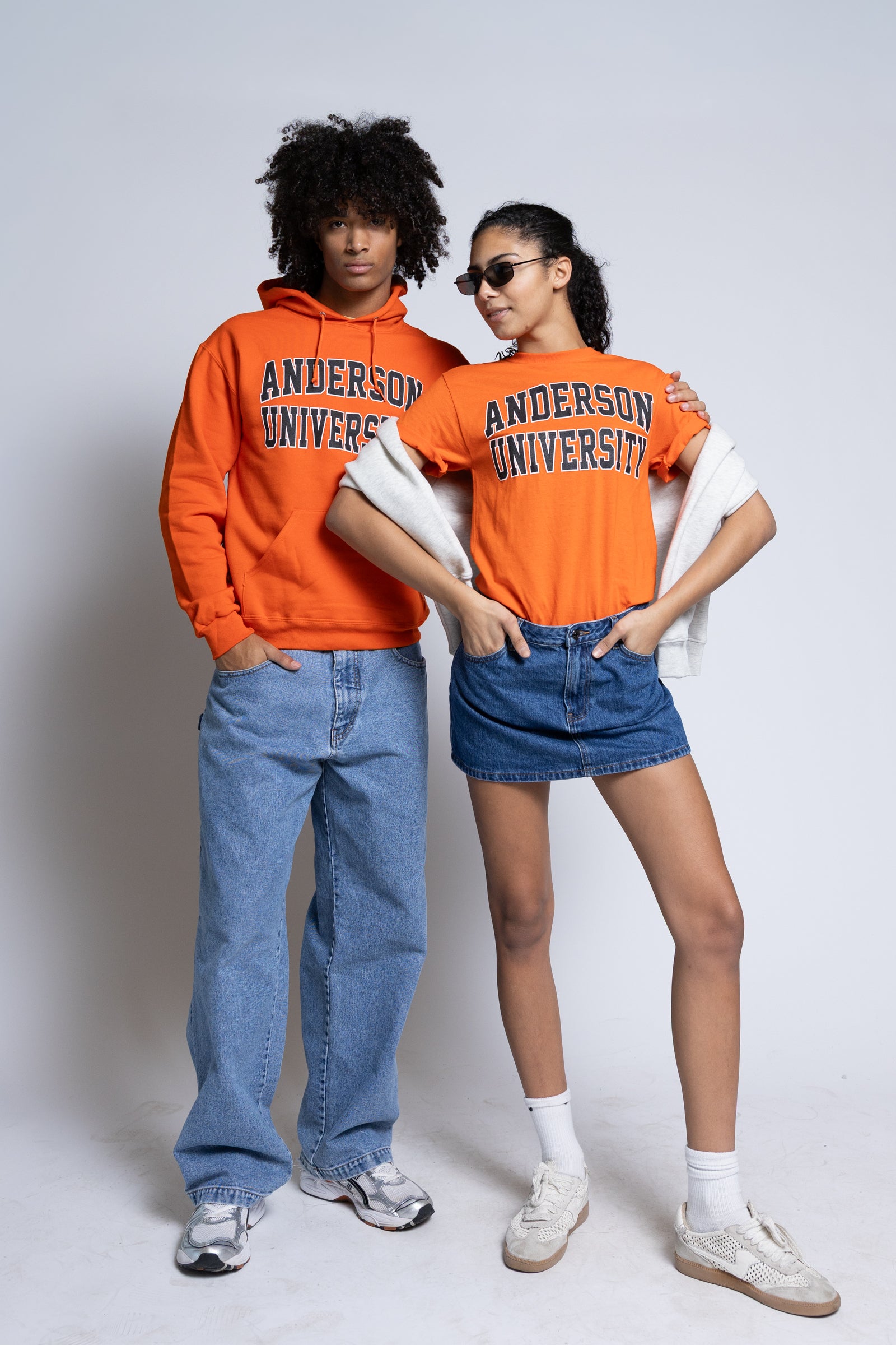 Two people wearing orange Anderson University clothing on a plain background