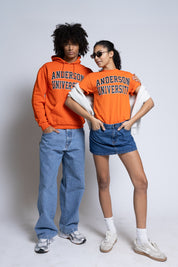 Two people wearing orange Anderson University clothing on a plain background