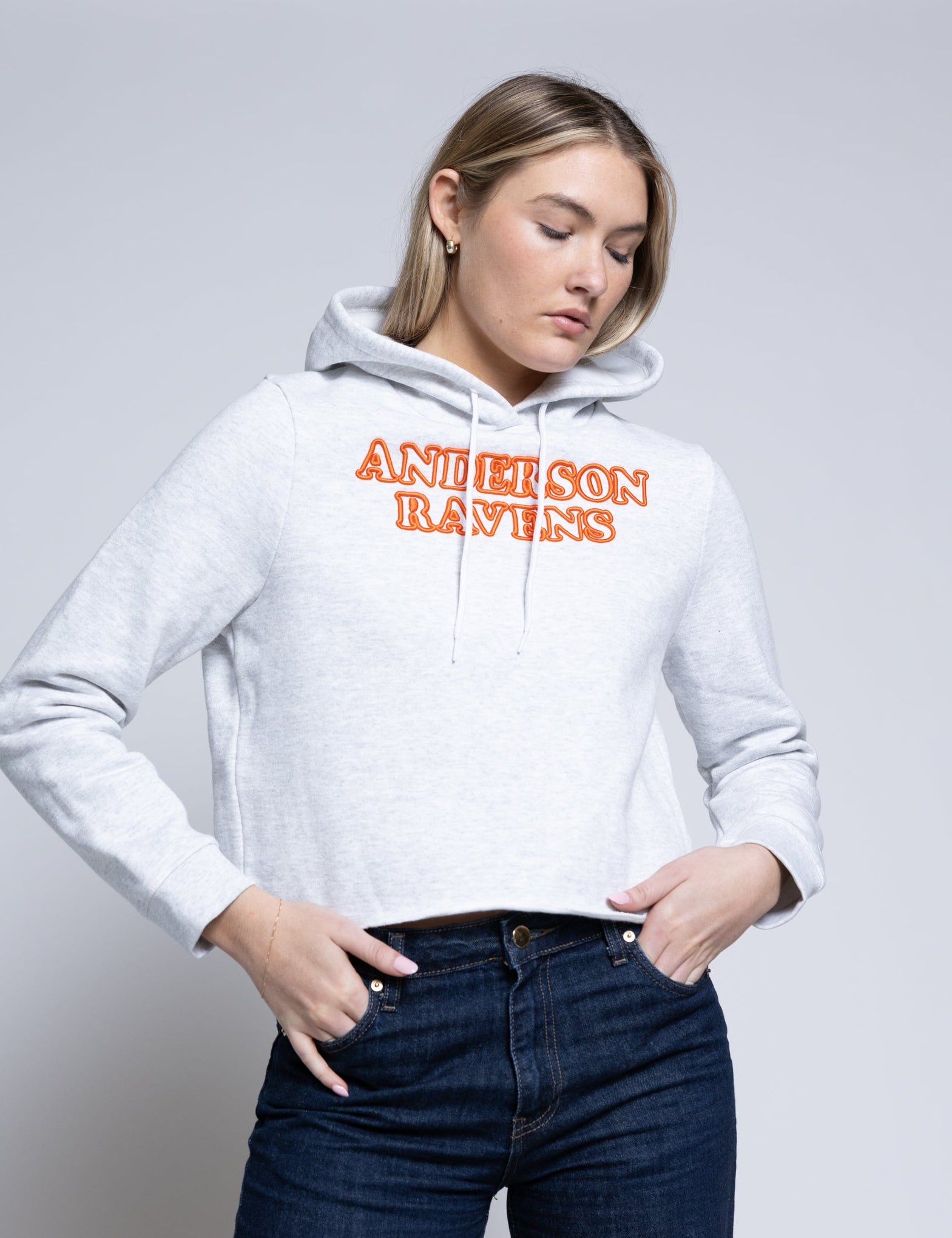Woman wearing a white hoodie with 'Anderson Ravens' text on a plain background