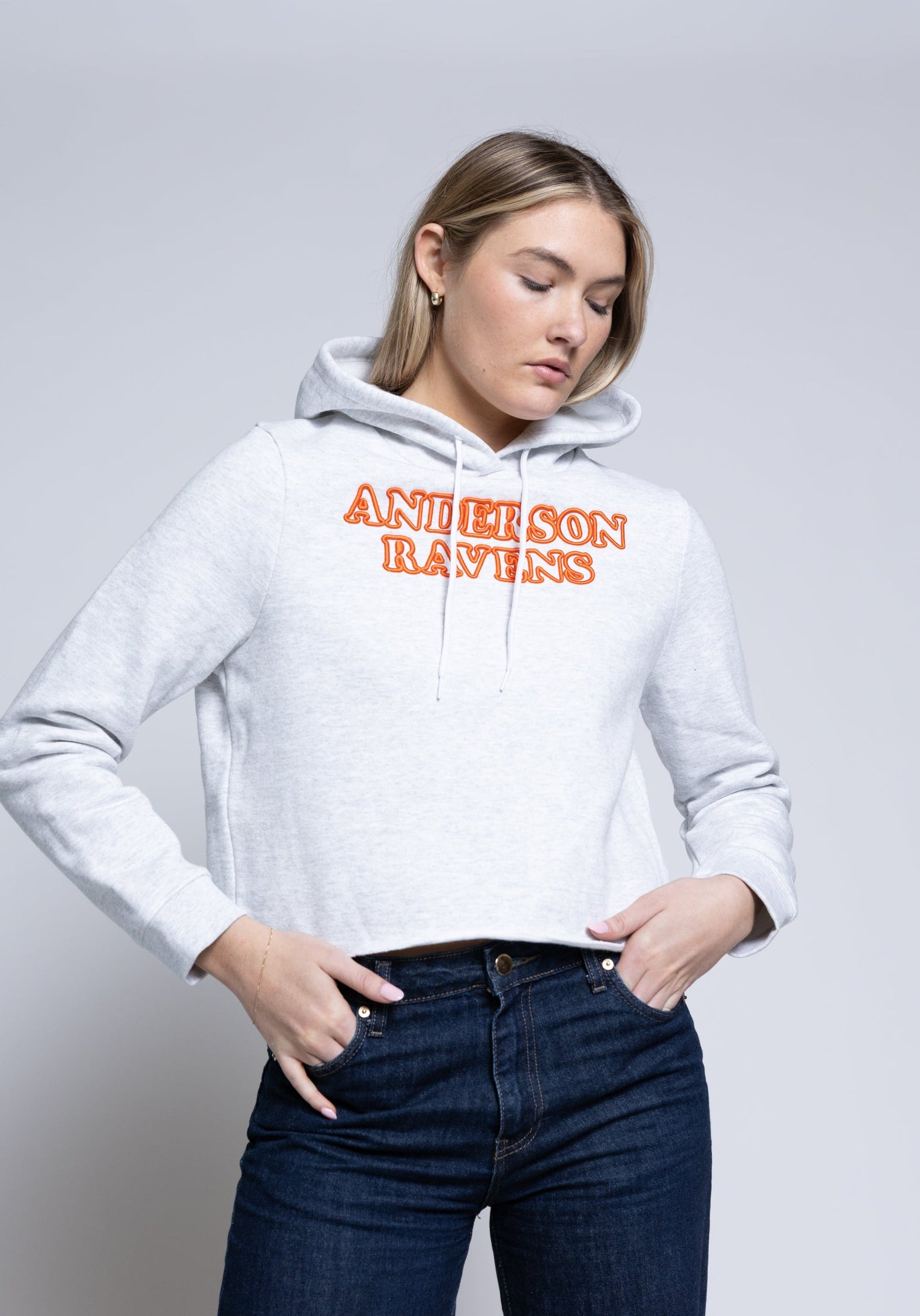Woman wearing a white hoodie with 'Anderson Ravens' text on a plain background