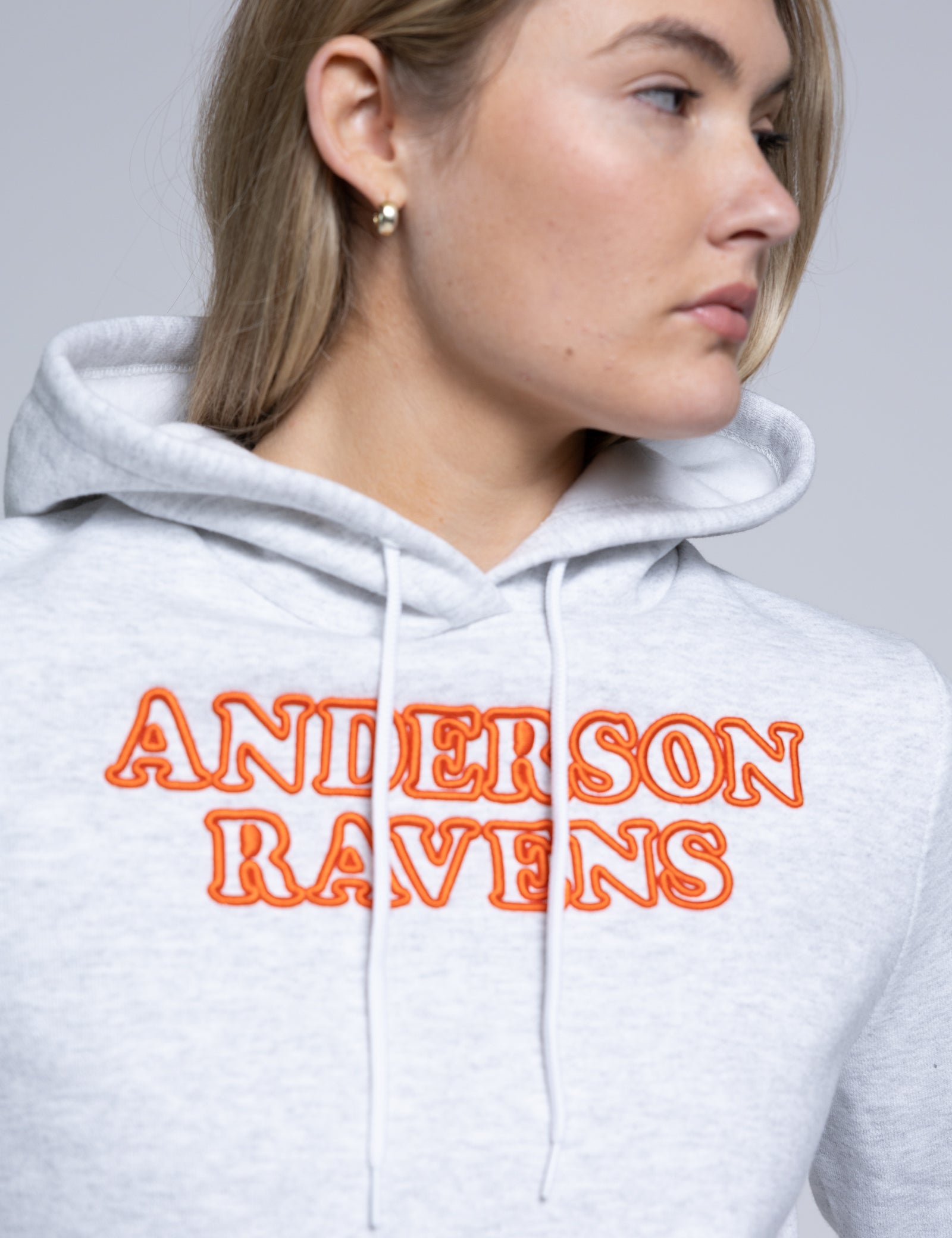 Person wearing a hoodie with 'Anderson Ravens' text in orange on a plain background