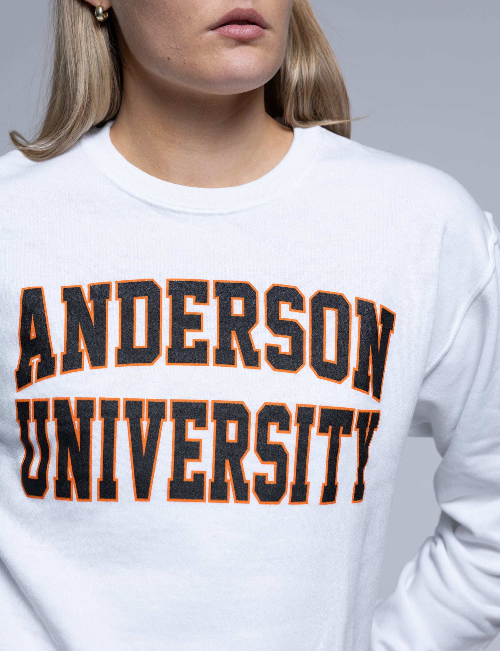 Person wearing a white crewneck with 'Anderson University' printed on it against a plain background