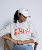 Person wearing a 'Anderson University' sweatshirt and cap on a white background