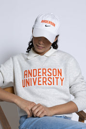 Person wearing Anderson University sweatshirt and cap sitting on a chair.